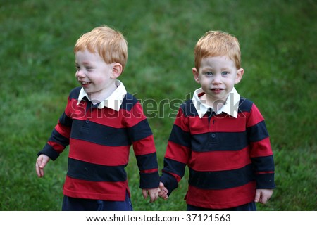 Twin baby boys holding hands outside