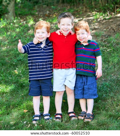 Three cute brothers standing outside on grass portrait