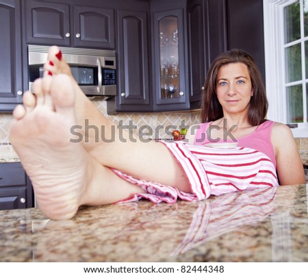 Attractive woman sitting in kitchen with feet on counter