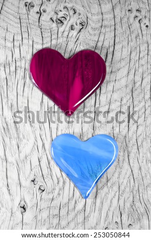 A couple in love - Cherry Red and Blue Glass Heart Symbols. Photographed on nautral wood background.