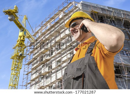worker in front of construction site talking on smart phone