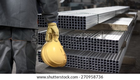 worker with helmet in production hall in front of steel sheet metal profiles