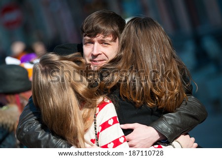 Young man embracing two girls on the street. All you need is love concept.
