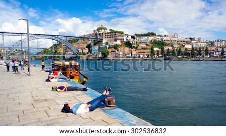 PORTO, PORTUGAL - JUNE, 14: Tourists relax at the embankment near famous landmark Luis bridge at day time on June 14, 2015 in Porto, Portugal