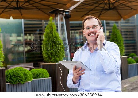 Middle age businessman using smartfone and tablet pc outdoors