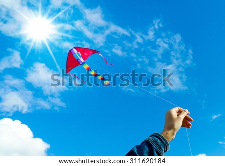 Hands holding kite in the cloudy sky. Focus to the hand