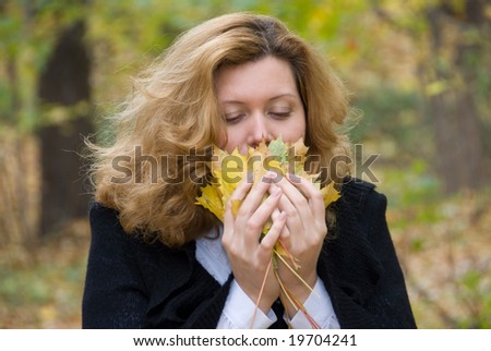 Middle age woman smells leaves in an autumn nature