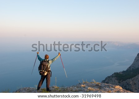 Hiker on a peak enjoys seashore landscape