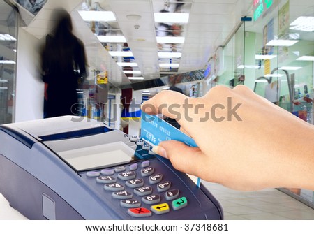 Human hand holding plastic card in payment machine in shop