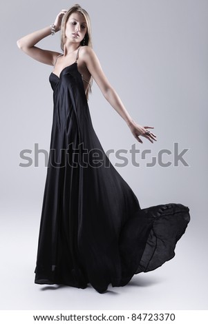 beautiful woman in black dress posing on neutral background