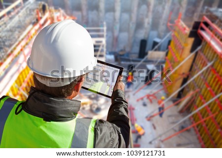 civil engineer or architect with hardhat on construction site checking schedule on tablet computer 商業照片 © 