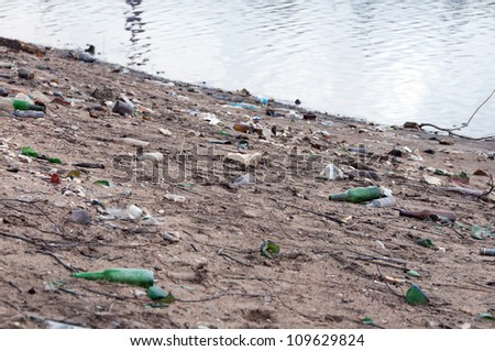 Stack of different types garbage on the river bank