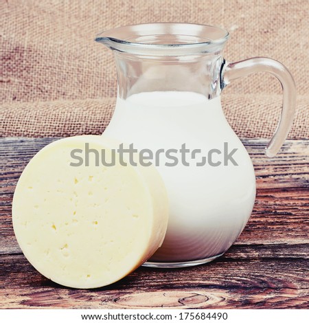 Glass jug with milk and piece of cheese