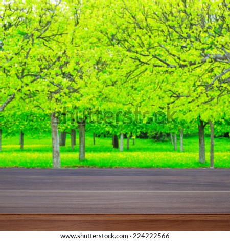Empty wooden desk and defocused spring forest for product display montages