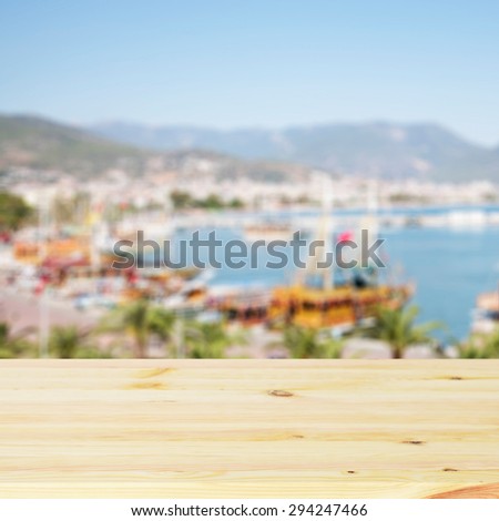 Empty wooden table. In the background blurred boats and yachts in the bay in sunny day