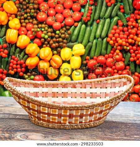 Empty basket on old wooden table.In the background blurred lot of ripe vegetables