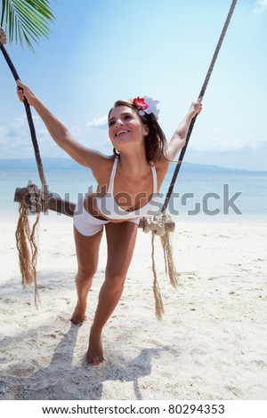 attractive woman in bikini  playing with swing on a sea background