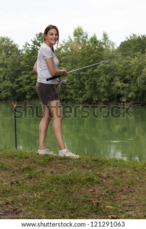 Brunette Woman Fishing at a lake with green water