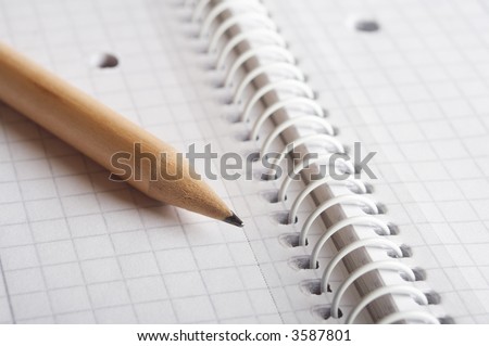 Wooden pencil on spiral bound notebook closeup. Room for your own text.