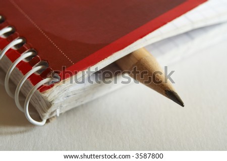 Wooden pencil sticking out spiral bound notebook. Room for your own text.