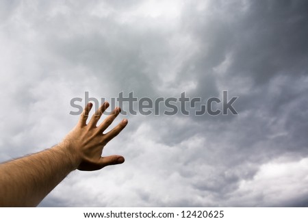 Hand touching stormy sky. Shallow DOF. Conceptual series.