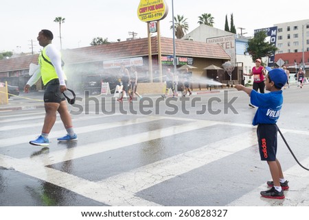 Los Angeles, California, USA - March 15, 2015: Unidentified volunteer boy throwing water in a runner
