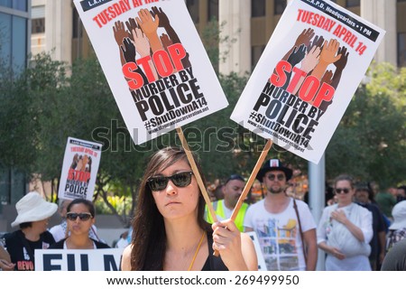 Los Angeles, CA, USA - April 14, 2015:  Woman holding two signs during Stop Murder by Police. Protest against the brutalization and murdering of black and latino people by police.