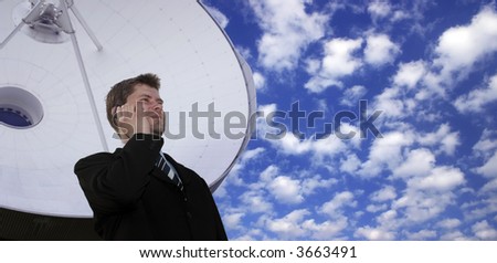 Successful businessman with cell phone in front of a huge satellite dish