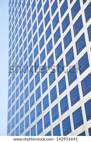 modern office building reflecting blue sky in many square windows