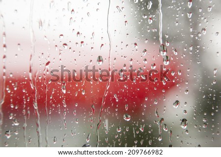 rain on window pane with a lot of red in the background