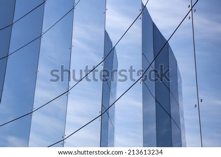 glass panes on facade of trade building reflecting blue sky and clouds