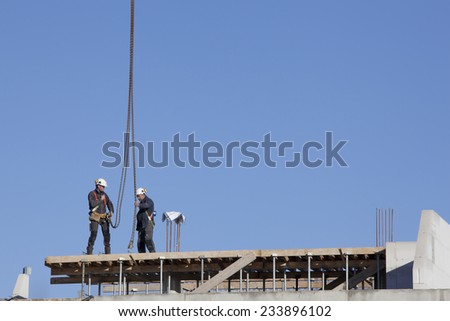 NIJKERK, NETHERLANDS, 24 NOVEMBER 2014: construction workers on roof of new building with blue sky