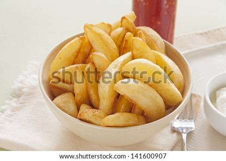 Bowl of freshly fried crisp potato wedges ready to serve.