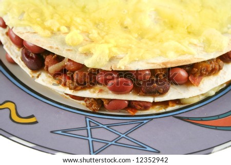 Background of a beef and bean Mexican tortilla stack with melted cheese.