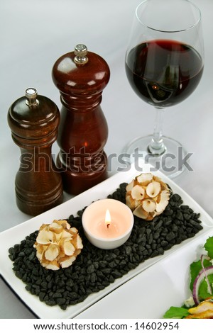 Salt and pepper grinders with a glass of red wine and a tea candle with decorations.