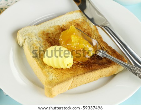 Dollops of orange marmalade and butter on a slice of toast.