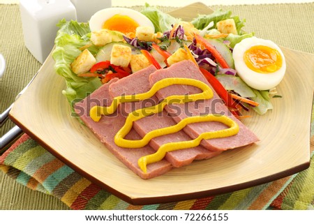 Sliced spam with mustard and a fresh garden salad.