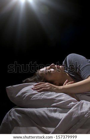 creepy glowing orb hovering over a woman sleeping in bed