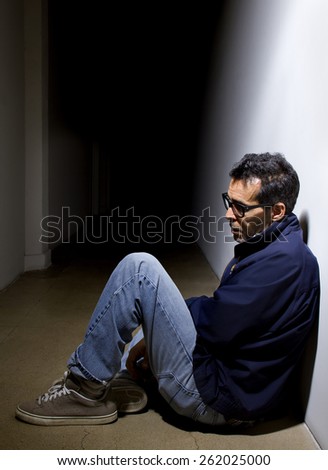 depressed man who lost faith sitting alone in a dark hallway