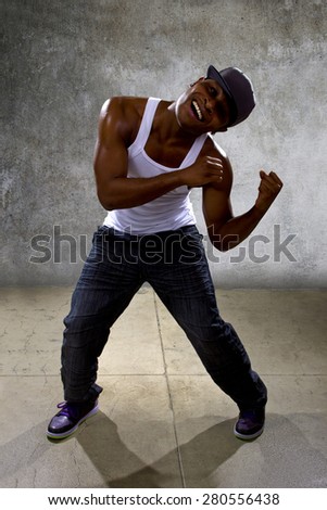 Muscular black man posing hip hop dance choreography on concrete background.  He is dancing in an urban setting.