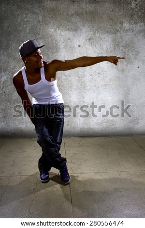 Muscular black man posing hip hop dance choreography on concrete background.  He is dancing in an urban setting.