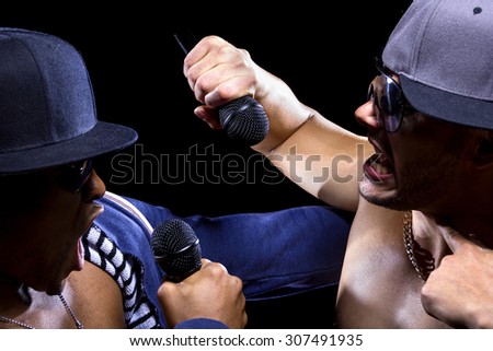 Hip hop subculture battle between two rappers with microphones.  The urban rappers are having a verbal battle.