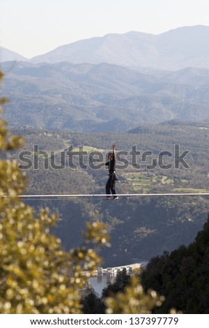 TAVERTET - APRIL 13: Man practicing highline in Tavertet, Spain on April 13, 2013. Highline is a balance sport that consists walking through a rope clamped between two points and great height below.