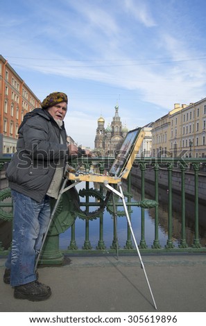 ST. PETERSBURG, RUSSIA - MARCH 24, 2014: Street artist on the background of the Griboedova canal and Church of the Savior on Blood