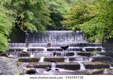 A multi-leveled waterfall surrounded by a forest of trees.