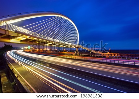 A multi-lane highway lit in the night time.