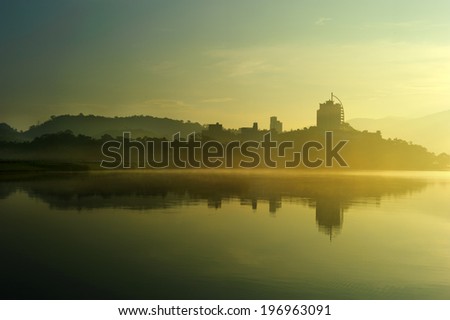 Trees and buildings reflected into a body of water.