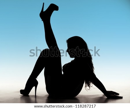 Silhouette of woman with long hair, with one leg raised above her head