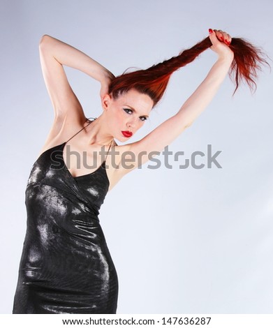 Red haired woman pulling her hair in a pony tail