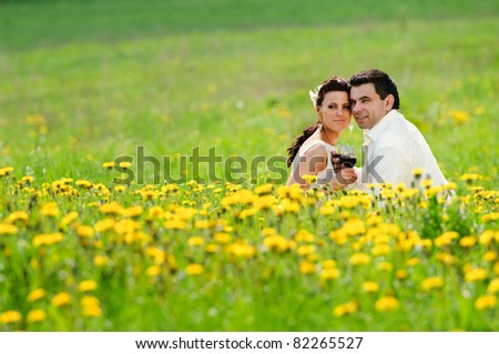 wedding couple with a glass in the field of dandelion